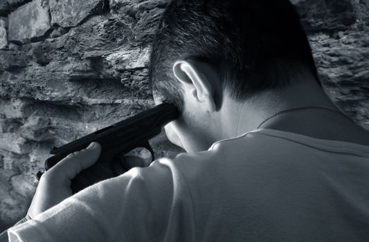 The man with a pistol on a background of a brick wall