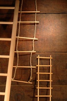 Three various ladders on old brown wooden background