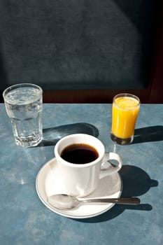 cup of coffee, glasses of water and juice on diner table.