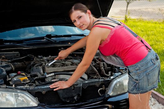 Young woman repairing her car