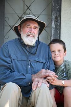 Elderly grandfather with his grandson sitting on a home porch