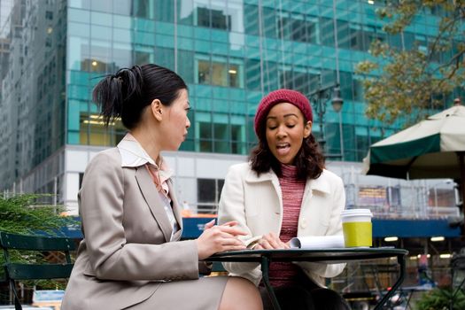 Two business women having a casual meeting or discussion in the city. 