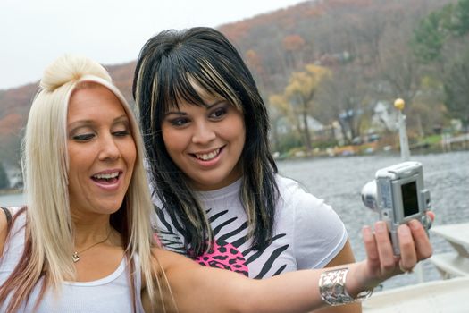 Two young women taking pictures of themselves with a digital camera.