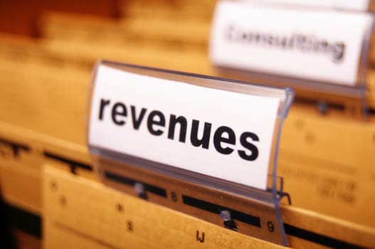 revenue or revenues word on business office folder showing financial success