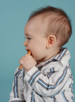 adorable 8 months cacasian baby boy eating a cookie