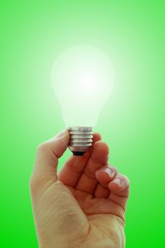 Glowing lightbulb in hand, green background