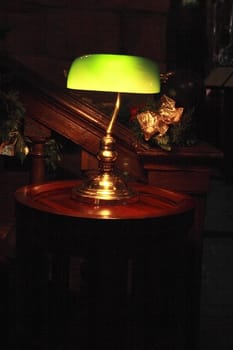 lit table lamp on a small wooden table  set in a dark surround