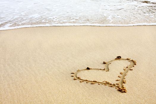 hearts drawn in the sand with seafoam and wave