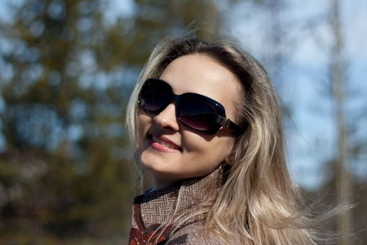 Beautiful smiling girl on background coniferous wood and blue sky