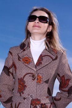 Pretty woman on background blue sky in sun-protective spectacles