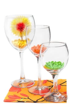 Three glasses with colour sweetmeat stand on orange napkin insulated on white background