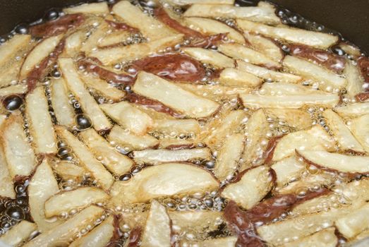 An order of french fries cooking in some oil.