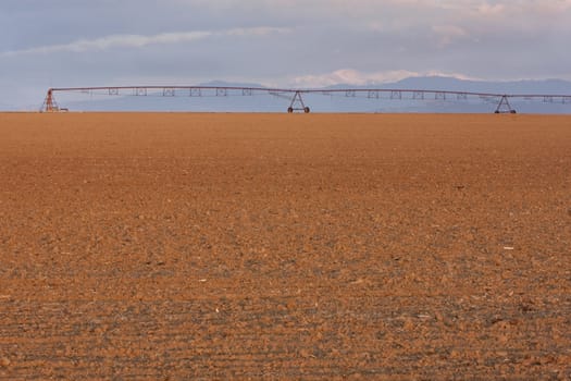 plowed field and irrigation equipment in northern Colorado with Rocky Mountains Front Range in background, sunrise light