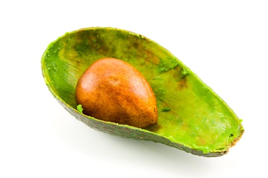 single dark green avocado fruit split in half scooped out and showing the kernel on a white background