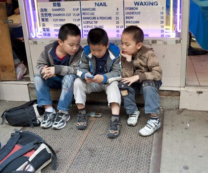 three boys in chinatown with handheld video game