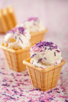 Delicious cone with vanilla icecream topped with lilac sprinkles