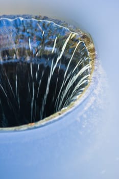 Water easy flowing down in round hole with blue sky reflection