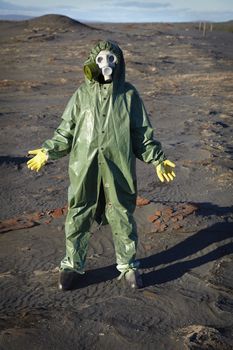 A man in a chemical protective suit stands in the desert