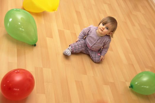 Small child sits in the middle of many colorful balloons, Copy Space
