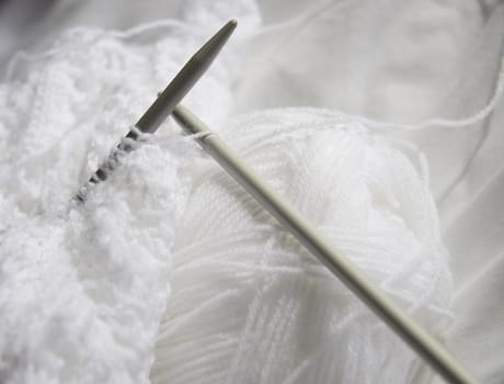 white wool and knitting with needles sticking out creating a shadow