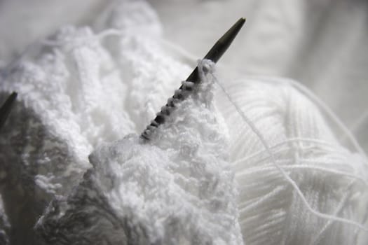 white wool and knitting with needles sticking out creating a shadow