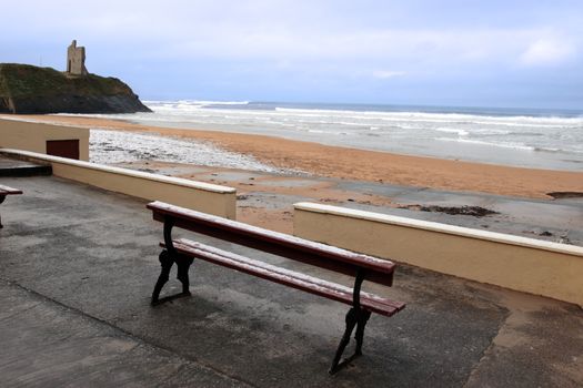 snow covered bench on the ballybunion beach in winter