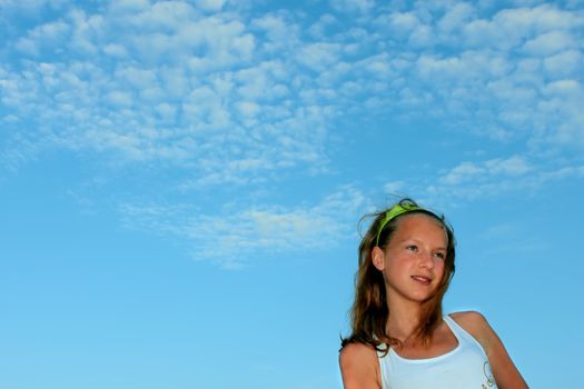 Teenage girl on the background of blue sky with clouds