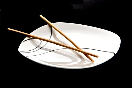 Wood chopsticks and asian style plate against black background