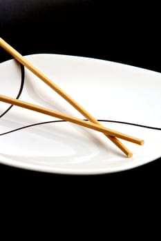 Wood chopsticks and asian style plate against black background