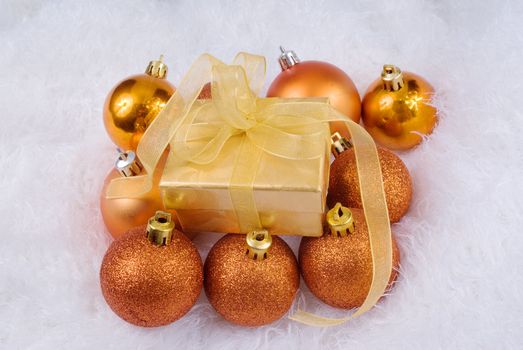 Christmas spheres and golden box on the white fur