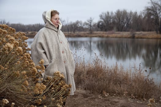 senior woman in her eighties enjoys a walk and watching wildlife  on a lake shore, nostalgic late fall scenery in Fort Collins, Colorado