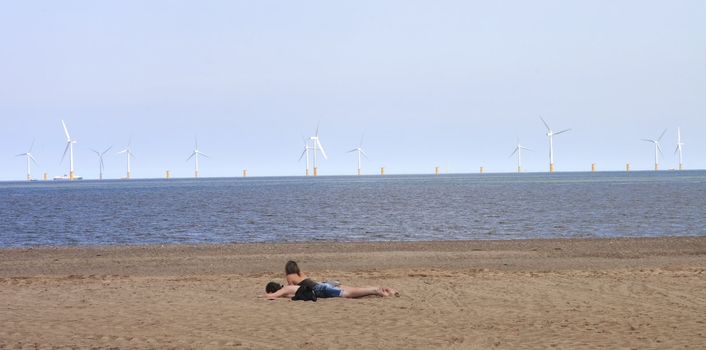 couple on the beach with a wind farm out to sea