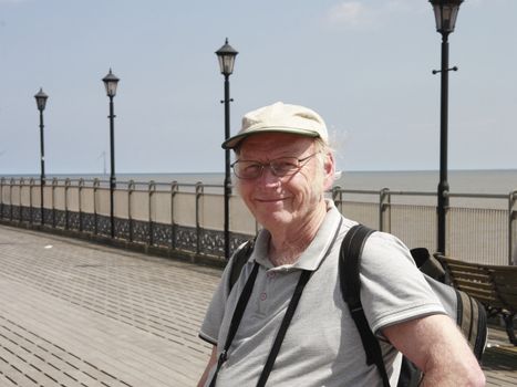 mature smiling man out for a daytrip standing on the pier