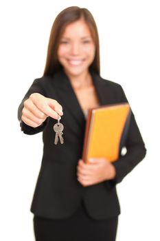 Real estate agent giving keys. Young realtor smiling handing over house keys to the new house owner, focus on keys. Isolated on white background.