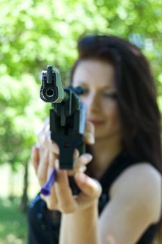 Woman aiming pneumatic gun, focus on gun point