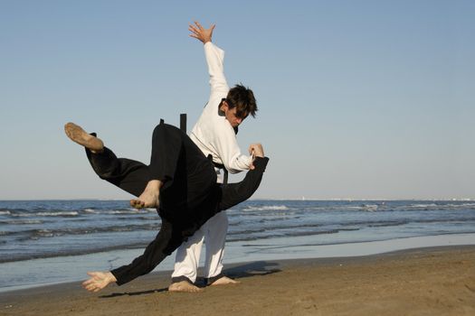 fighting of two men in taekwondo and apkido sports on the beach