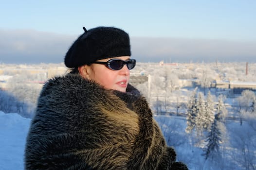 Woman in fur coat against the background of winter cityscape