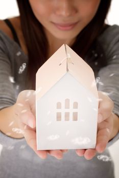Family concept by young woman holding house model on hand.