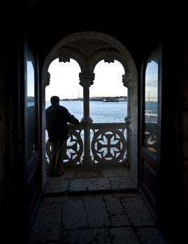 man looking out over the ocean from a balcony of the Torre de Belem