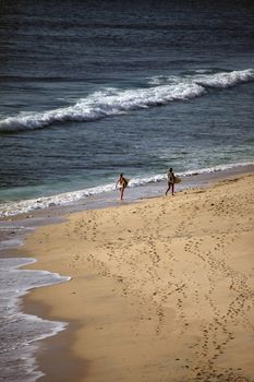 Two girls with boards for surfing at coast of the Indian ocean. Dreamland beach - Bali