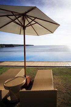 Wicker chairs on a Dreamland beach. The edge of pool merges with ocean
