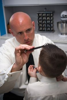 A groom helps his son get ready by doing his hair.