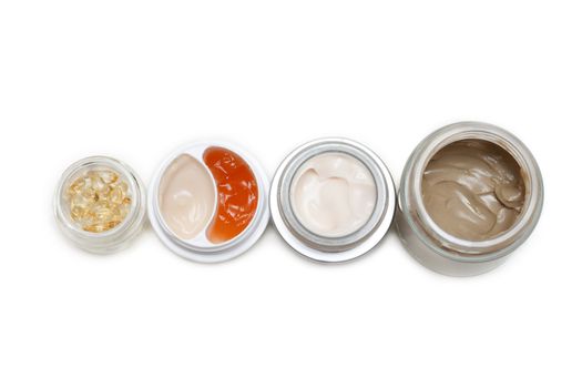 Opened banks with make-up cream on white background