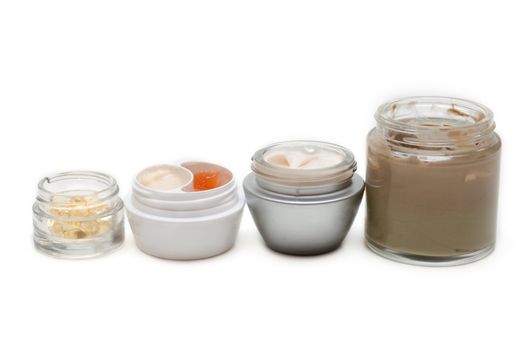 Opened banks with make-up cream on white background