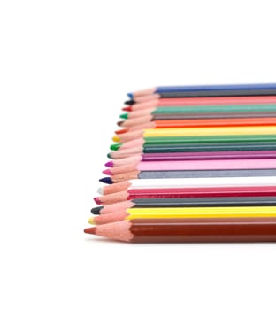 Crayons lies in row on white background with small depth of the sharpnesses