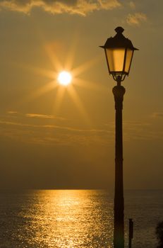 Sun reflected on the sea and streetlight at sunset in Mediterranean sea