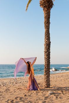 Oriental dancer with fluttering headscarf on beach setting