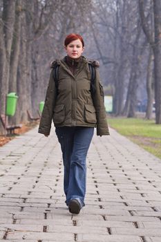 Image of a redheaded teenager walking in an autumn park.Shot with Canon 70-200mm f/2.8L IS USM