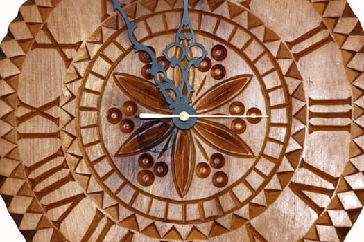 Detailed view of a handmade clock carved on wood showing time five minutes before twelve