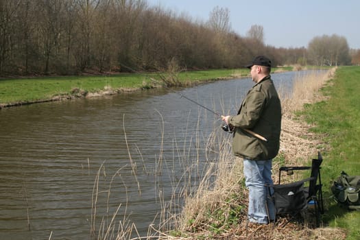 Man standing by the waterside with his fishing rod